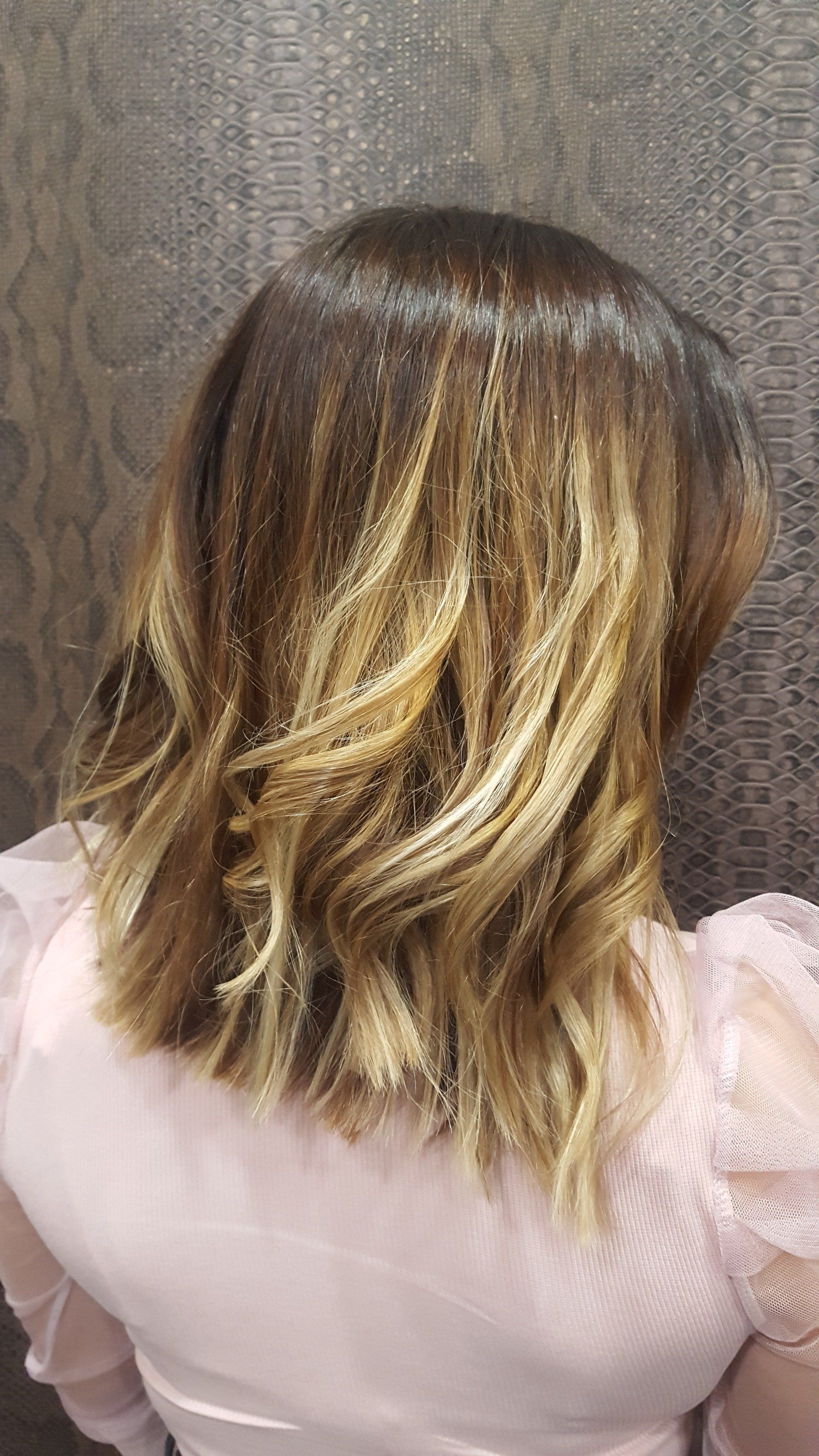 La parte posterior de la cabeza de una mujer con cabello rubio y una camisa rosa.