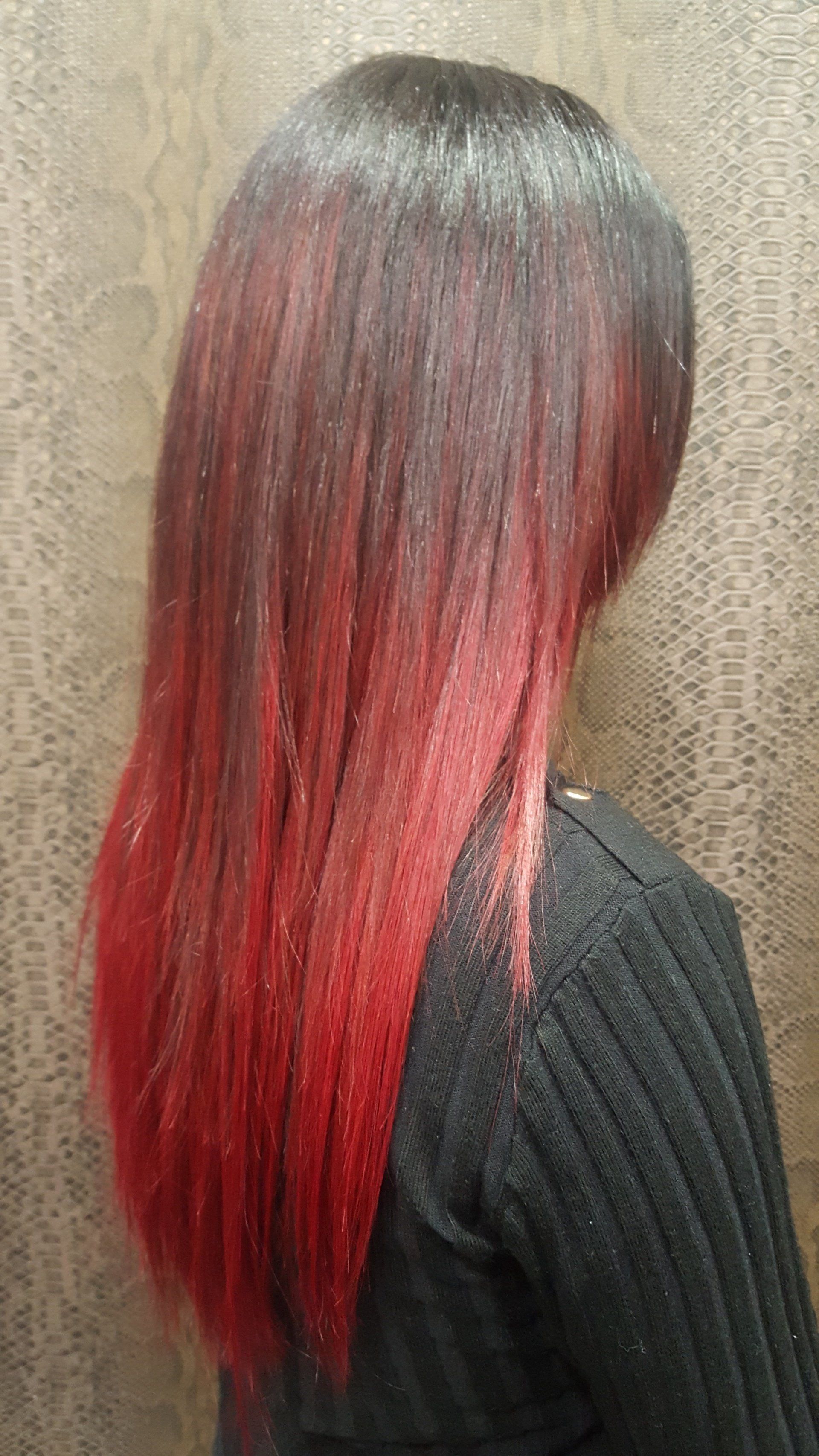 Una mujer con cabello largo y rojo lleva un suéter negro.