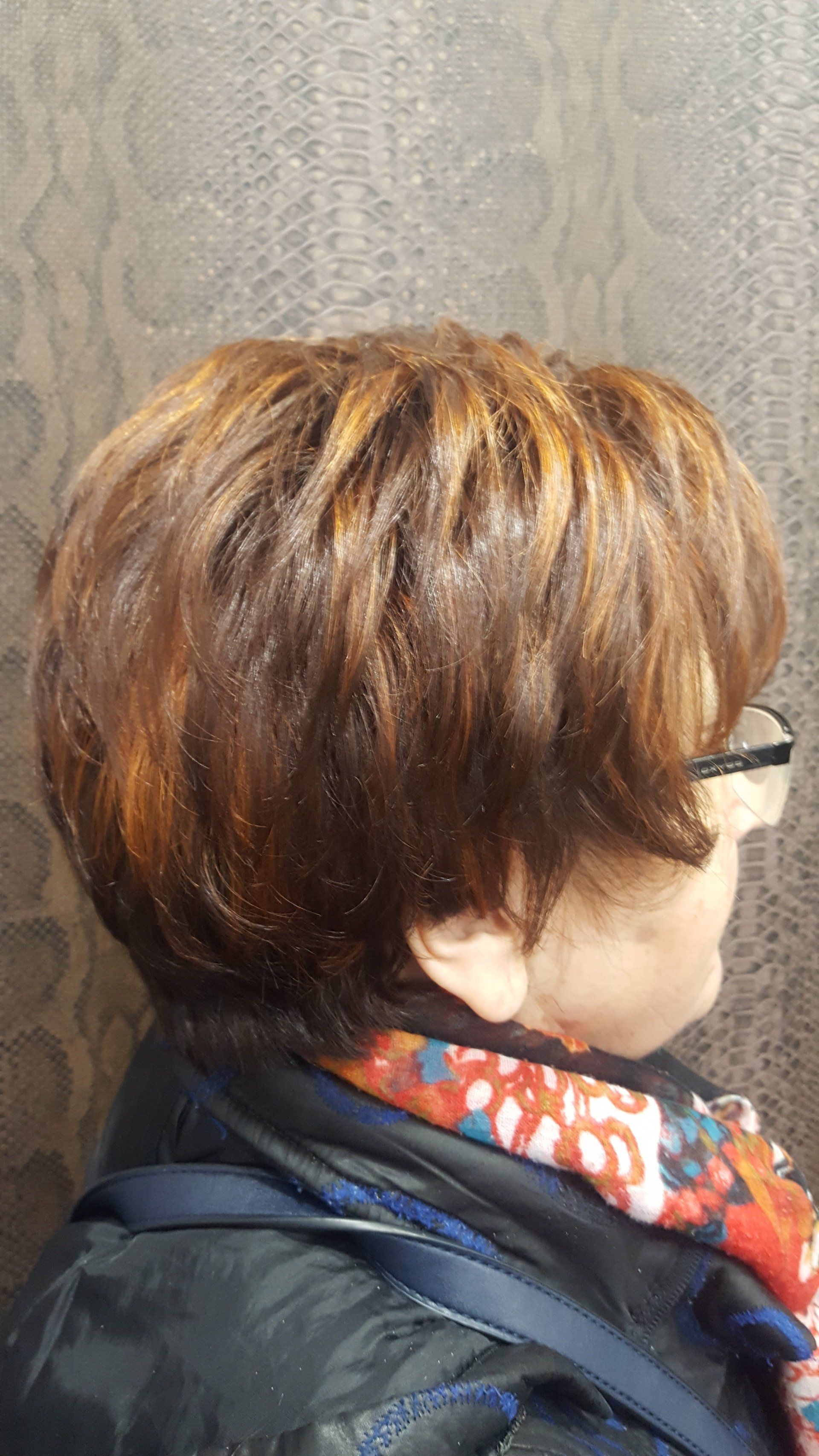 Una mujer con pelo corto y gafas lleva una bufanda y una chaqueta.