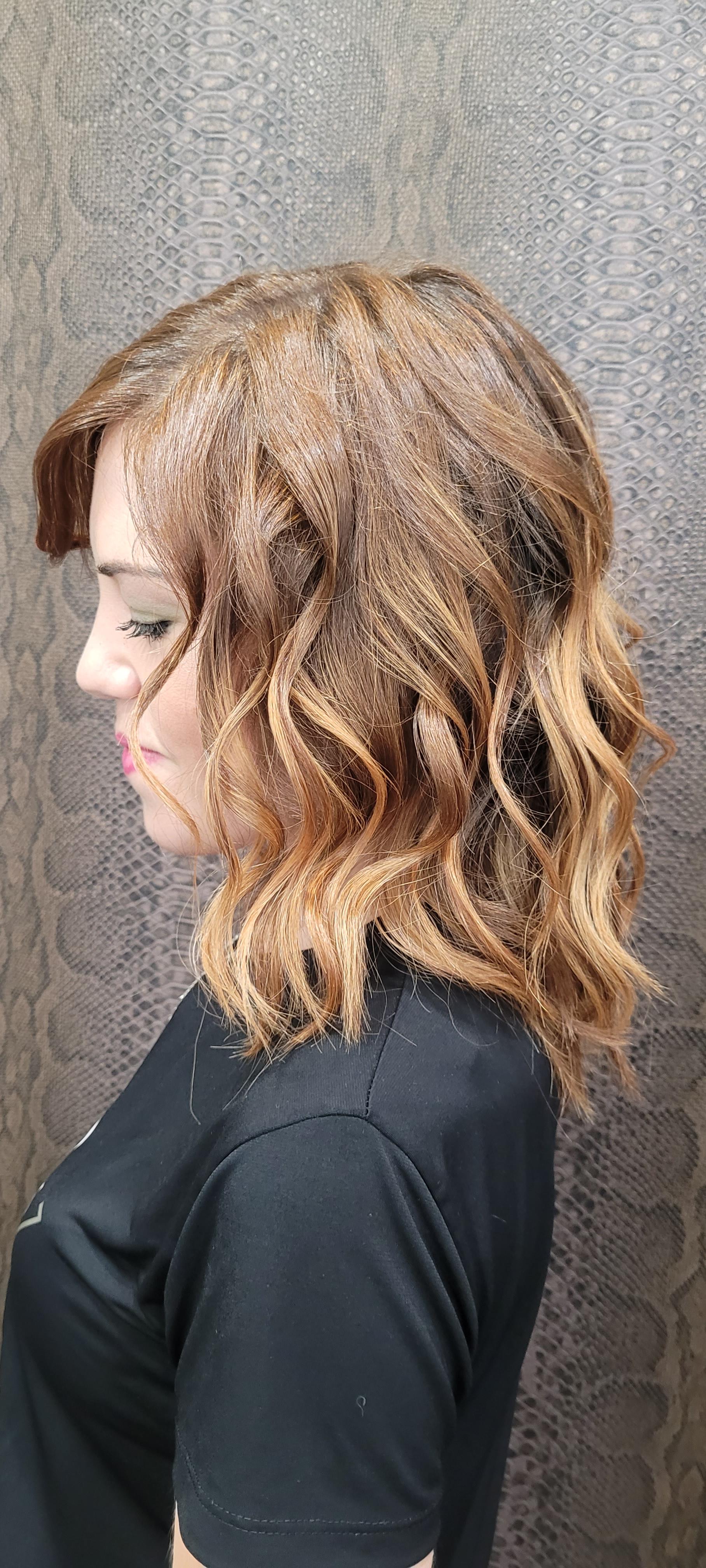 Una mujer con cabello rubio lleva una camisa negra y está parada frente a una pared.