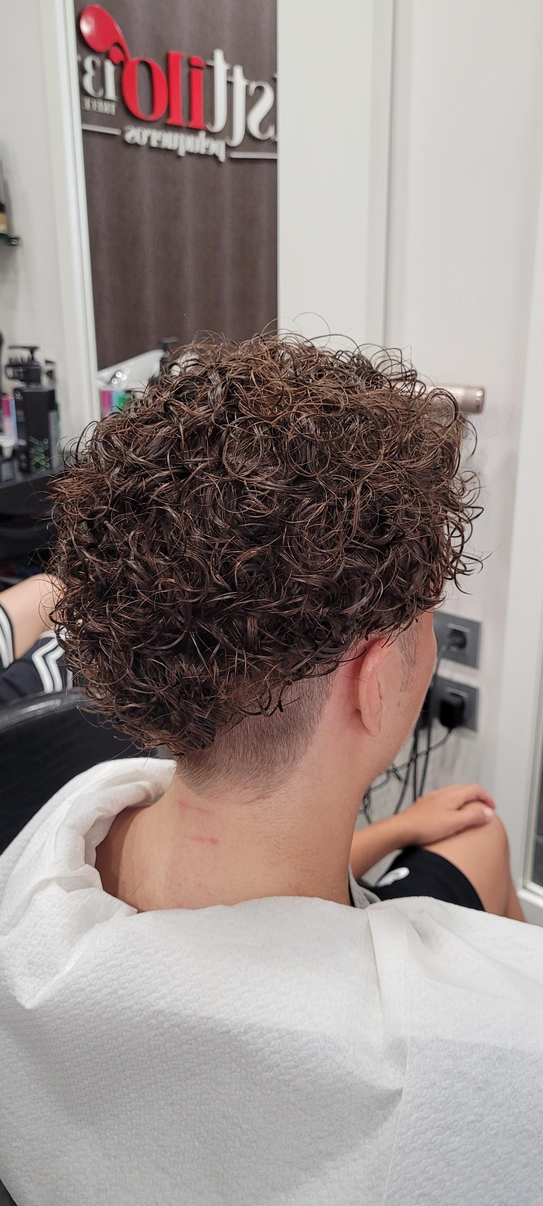 Una mujer con cabello rizado está sentada en una silla en un salón.