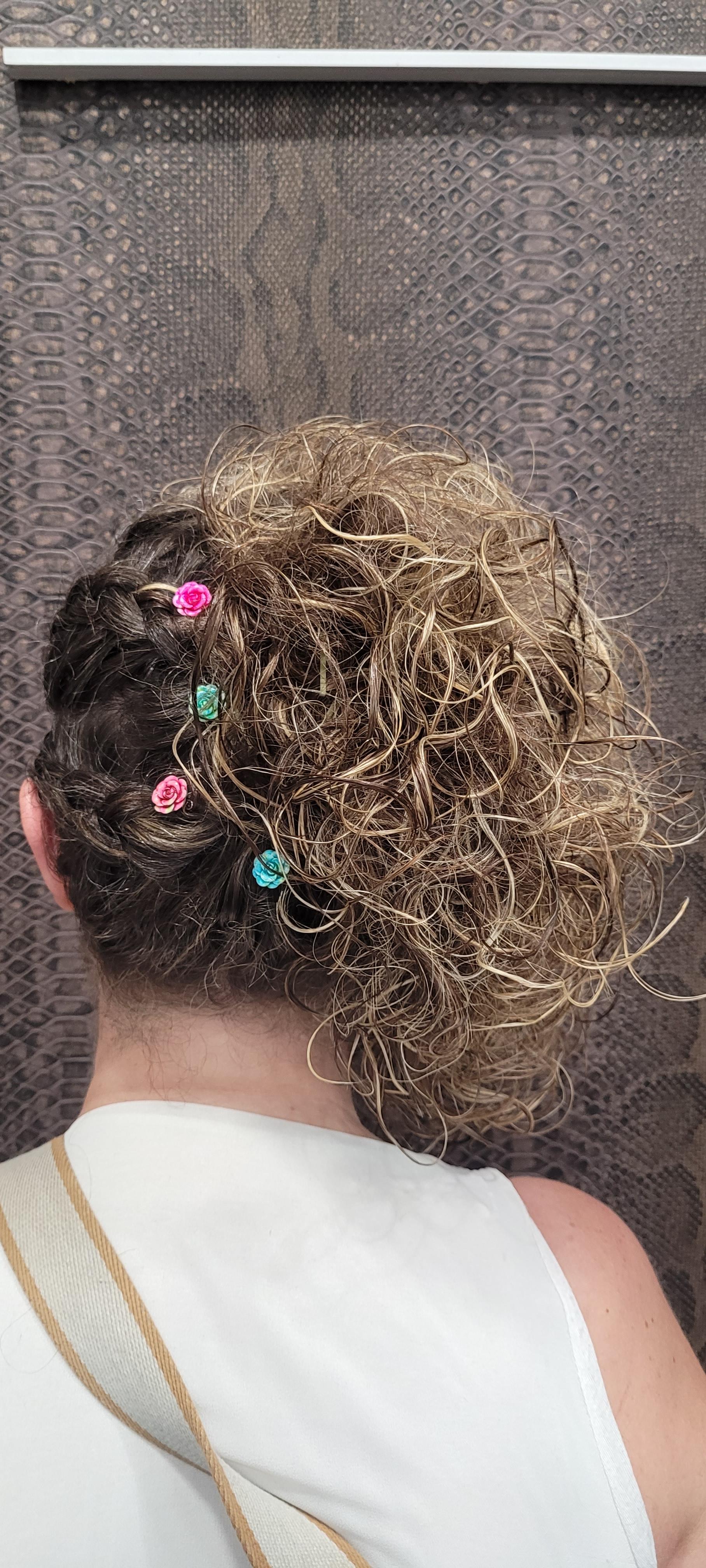 Una mujer lleva una camiseta blanca sin mangas y tiene el pelo recogido en un moño.