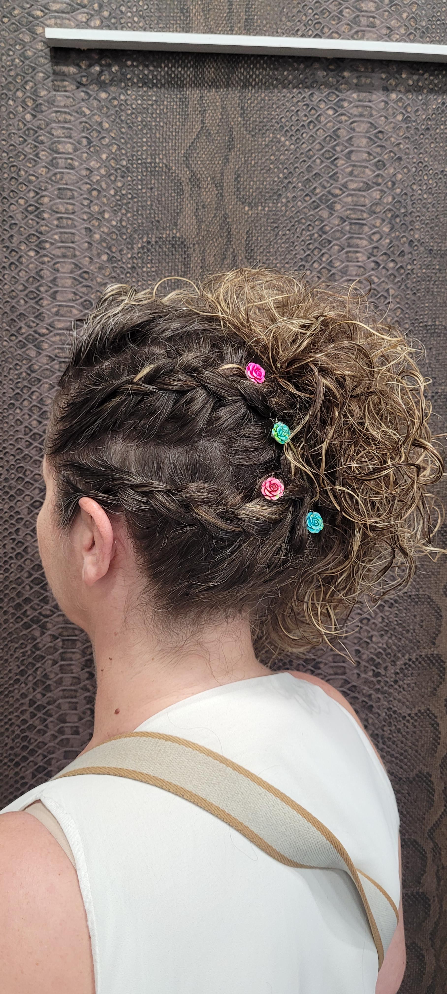 Una mujer con cabello rizado lleva una camiseta blanca sin mangas y un moño.