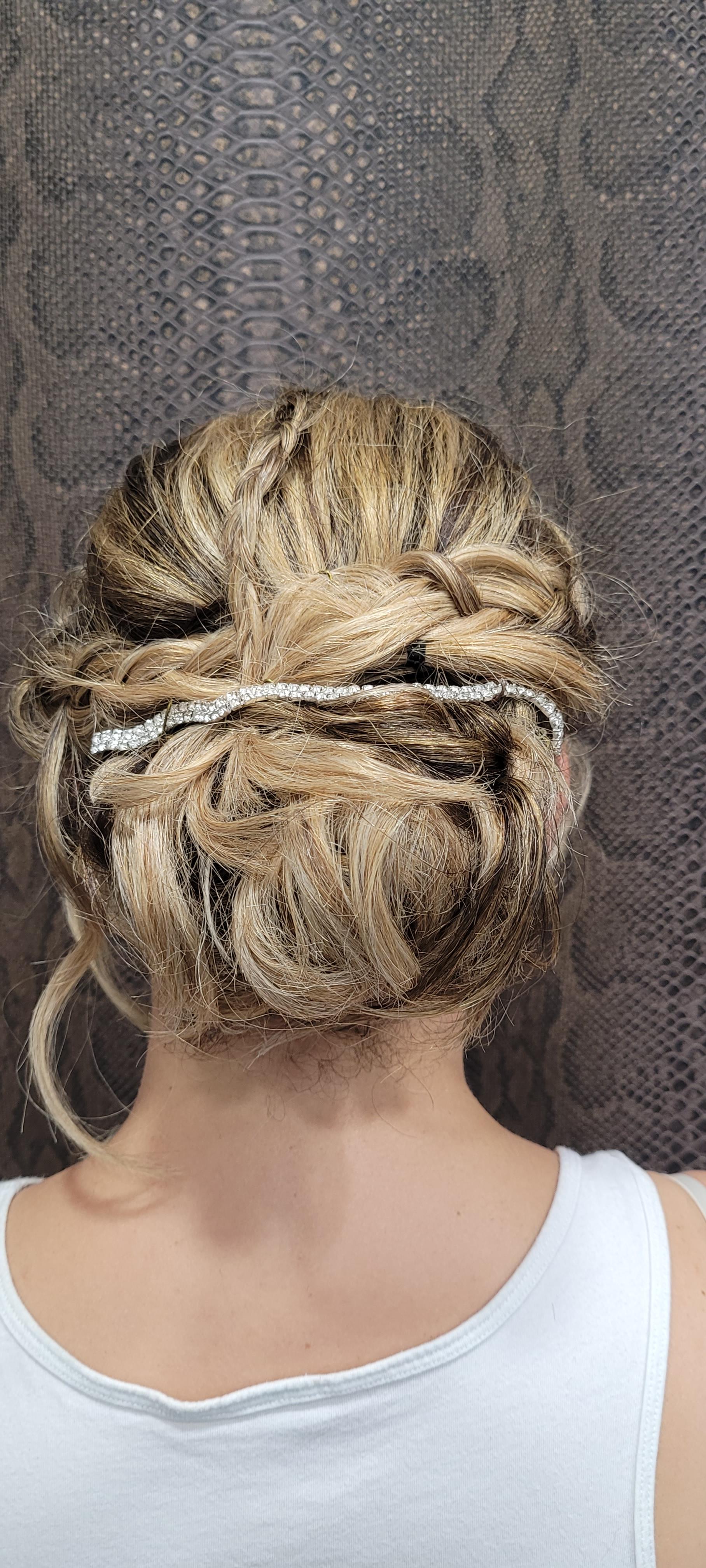 La espalda de una mujer que lleva una camiseta blanca sin mangas y el pelo recogido en un moño.