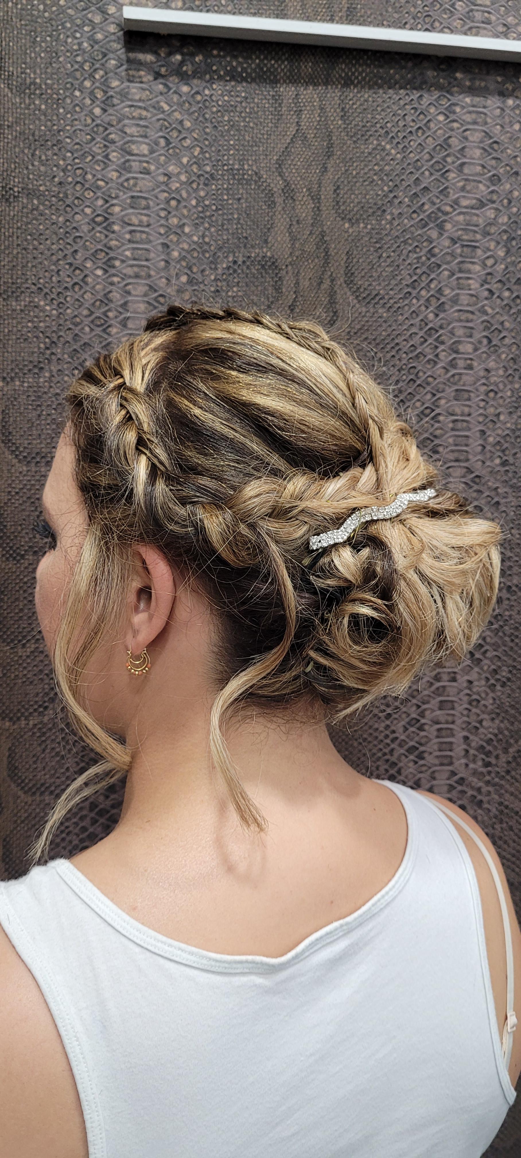 Una mujer lleva una camiseta blanca sin mangas y tiene el pelo recogido en un moño.
