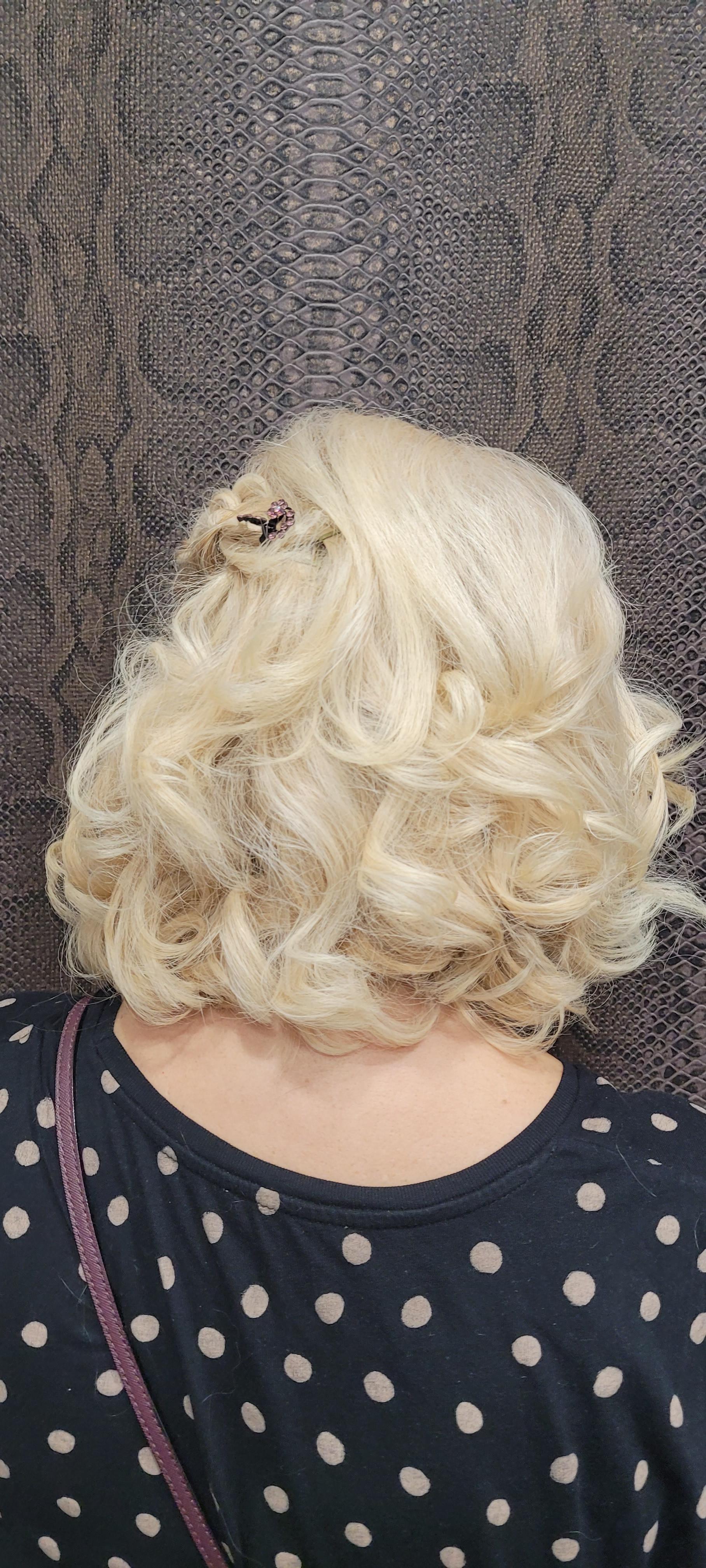 La parte posterior de la cabeza de una mujer con cabello rubio y una camisa de lunares.