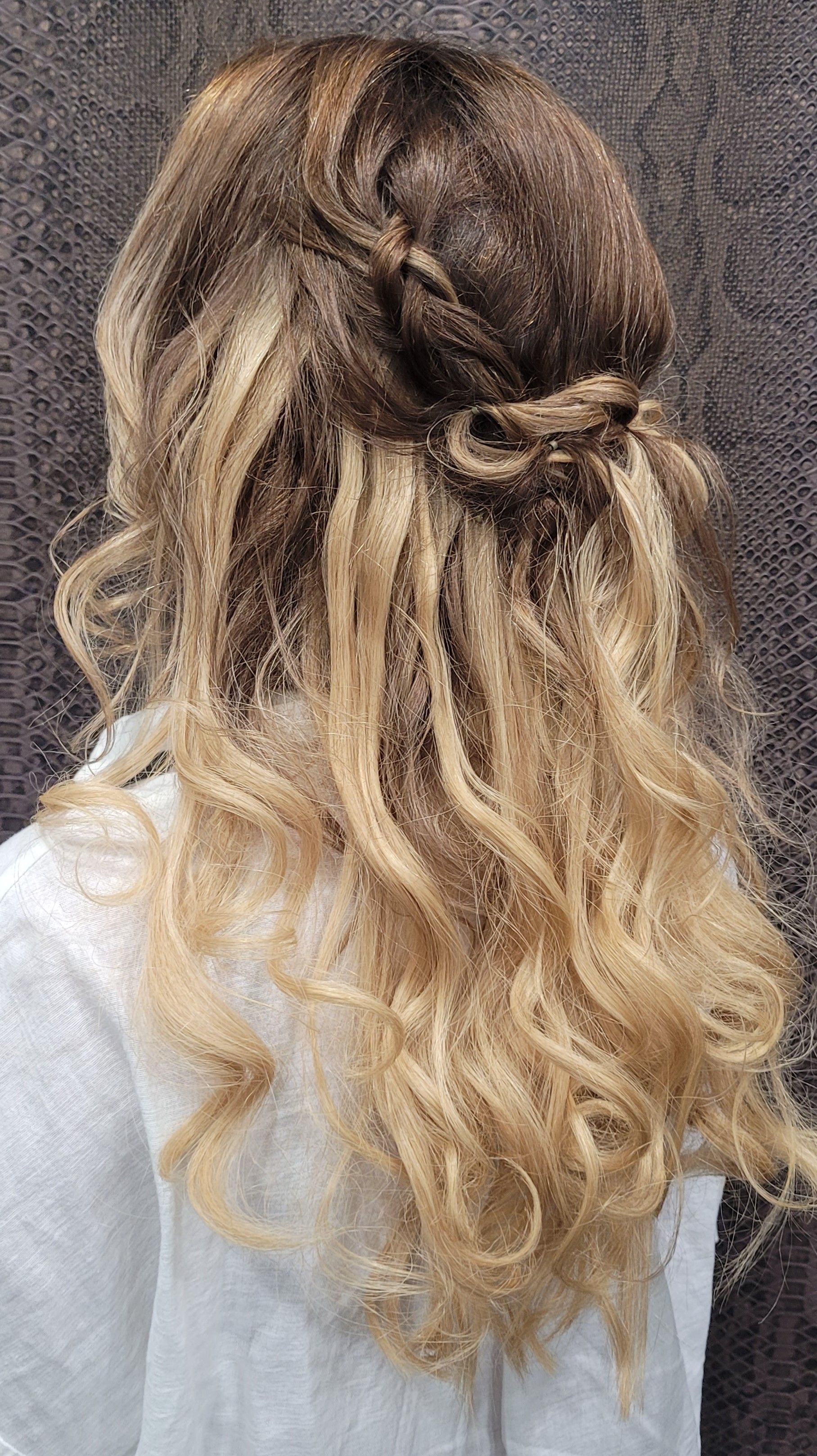 Una mujer con cabello largo y rubio lleva un peinado mitad recogido y mitad suelto.