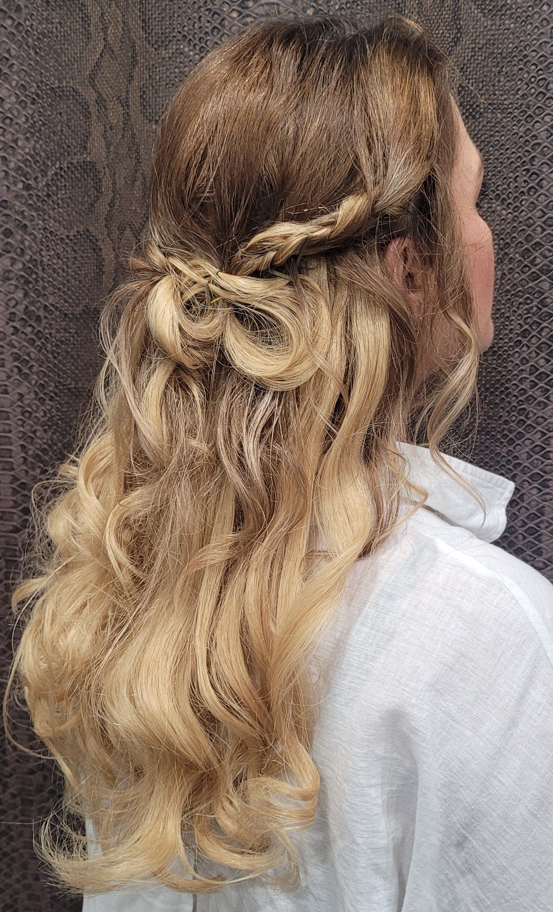 Una mujer con cabello largo y rubio lleva un peinado mitad recogido y mitad suelto.