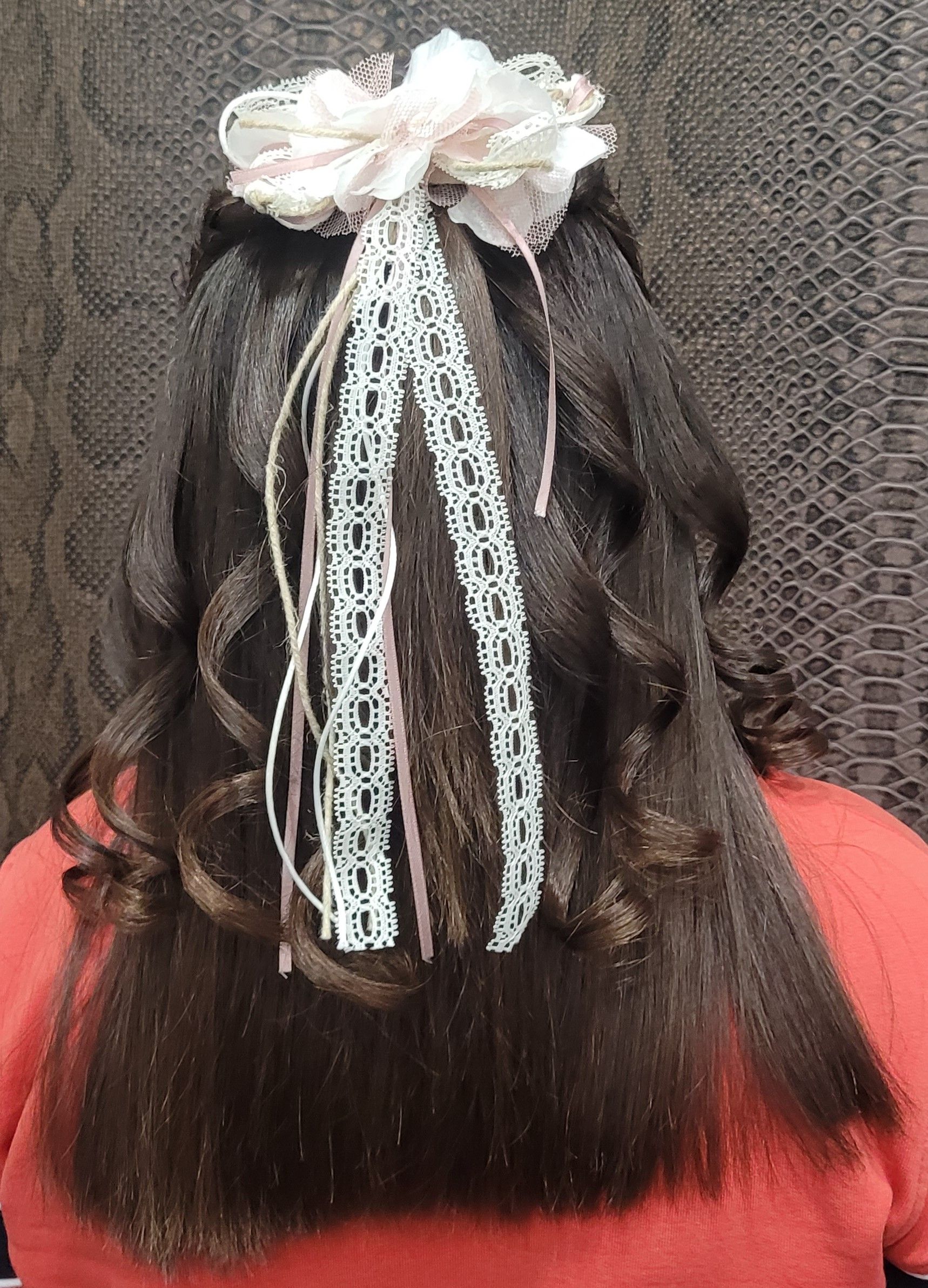 La parte posterior de la cabeza de una niña con una flor en el pelo.