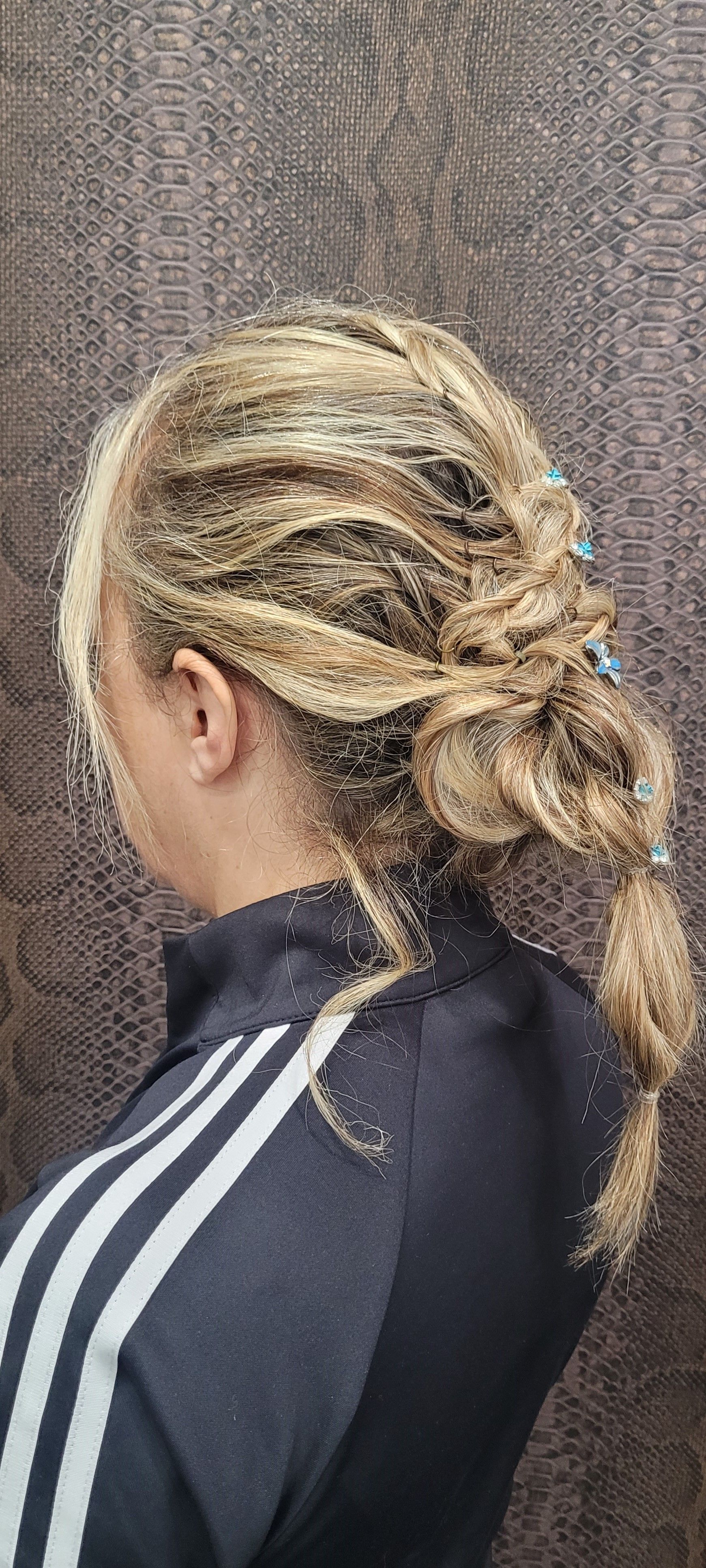 Una mujer con cabello rubio lleva una sudadera con capucha negra y una cola de caballo trenzada.