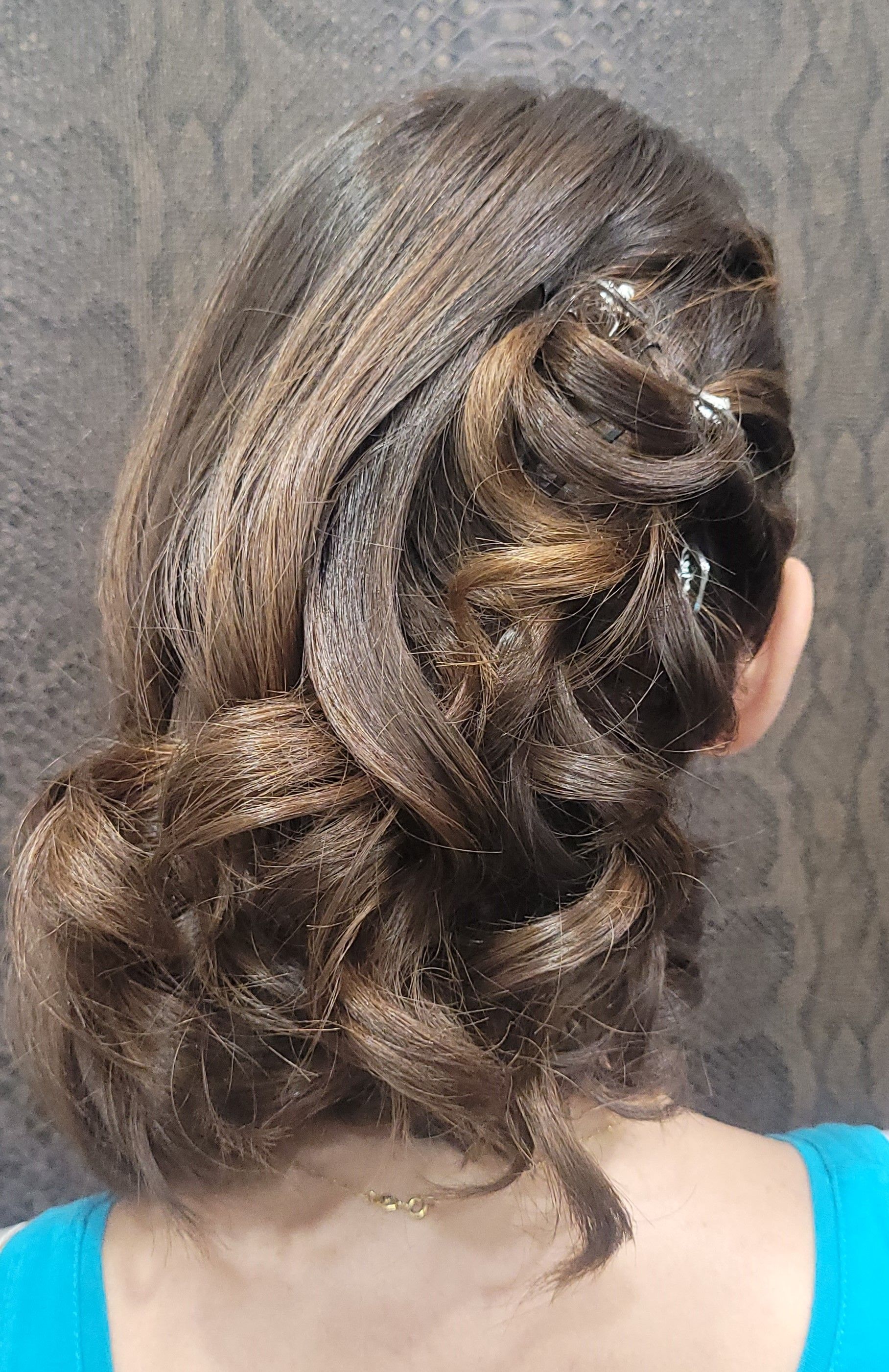 Una mujer lleva el pelo recogido en un moño y una camisa azul.