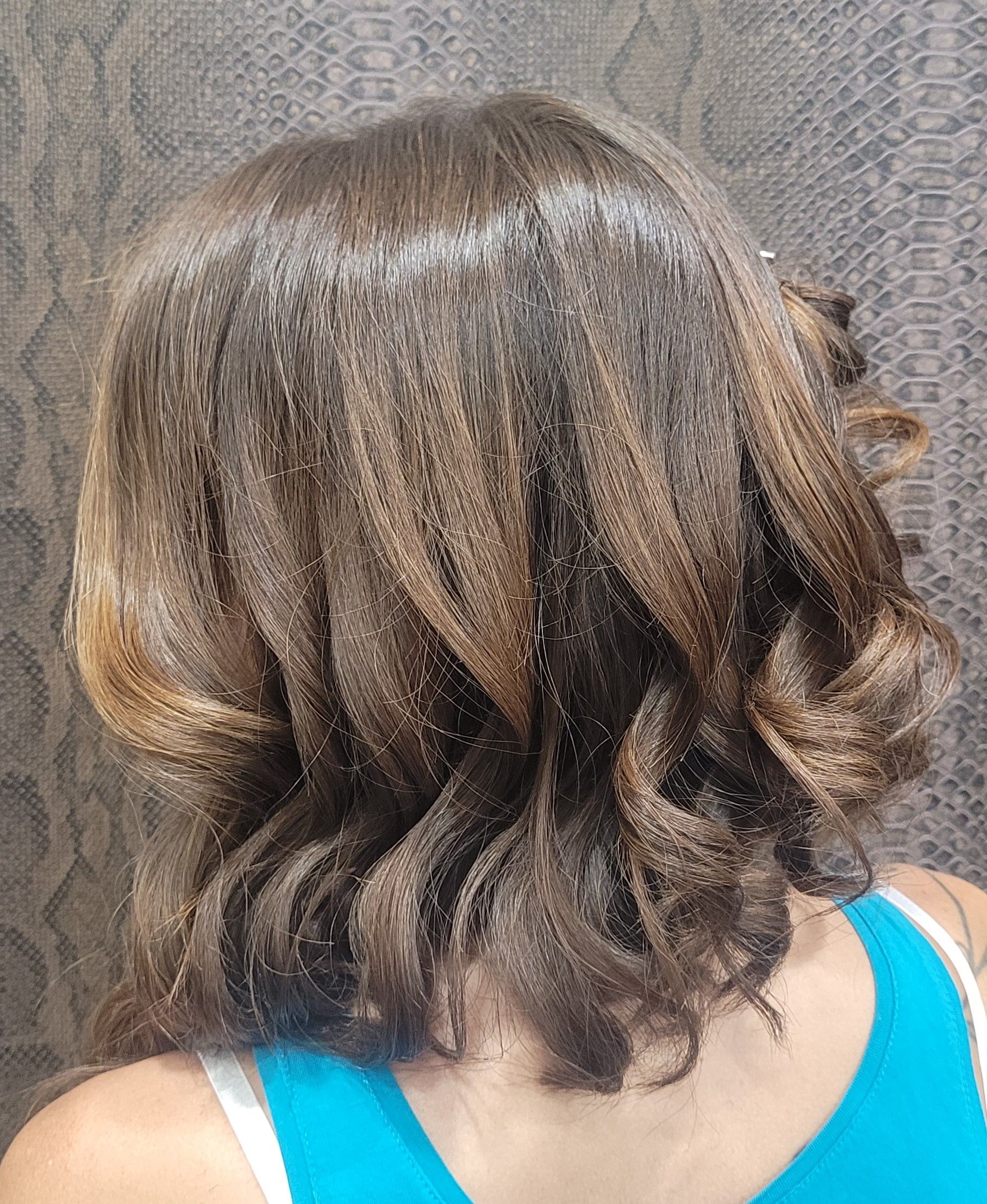 Una mujer con cabello largo y castaño lleva una camiseta azul sin mangas.