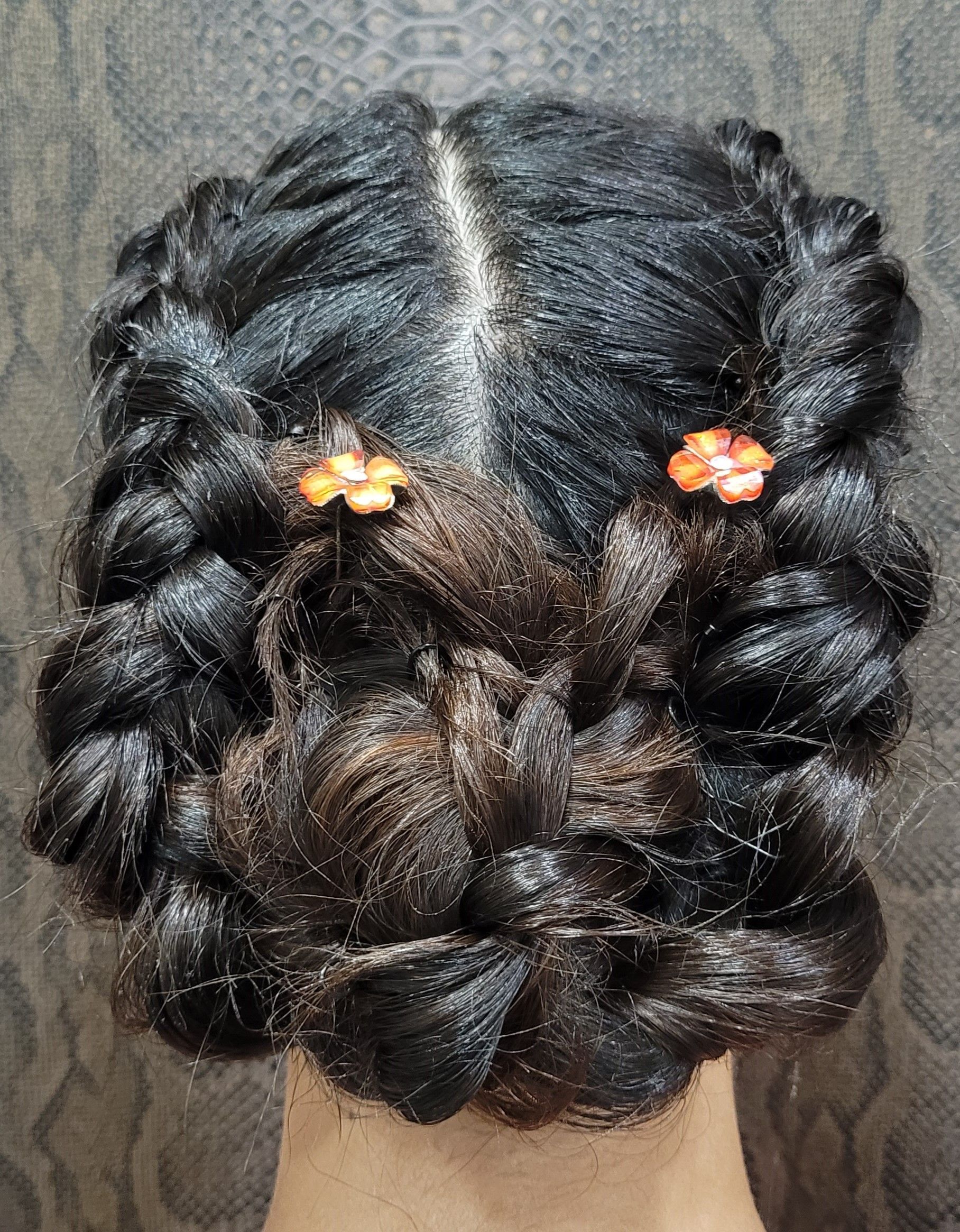 La parte posterior de la cabeza de una mujer con trenzas y flores en el cabello.