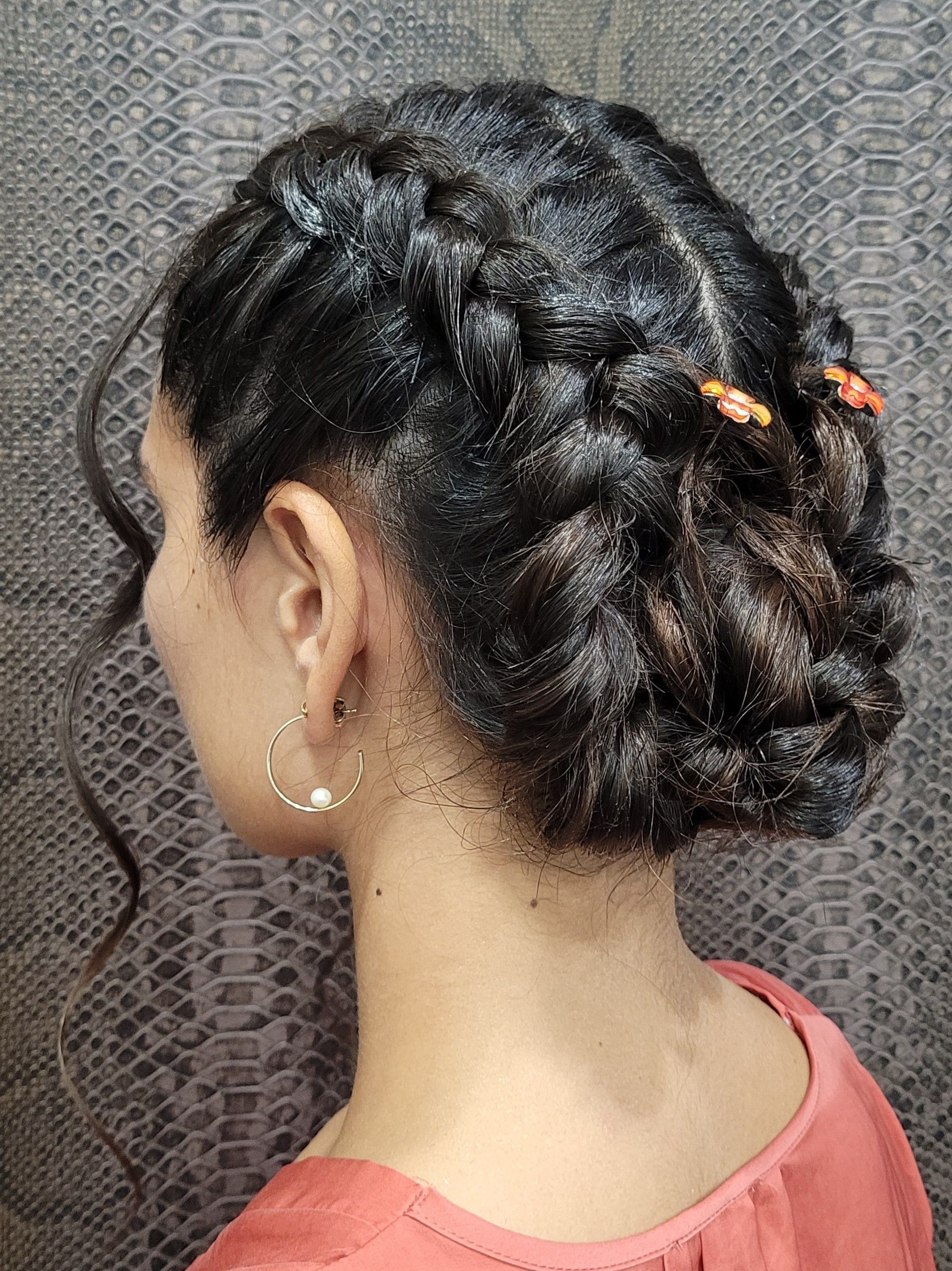Una mujer lleva un moño trenzado y pendientes.