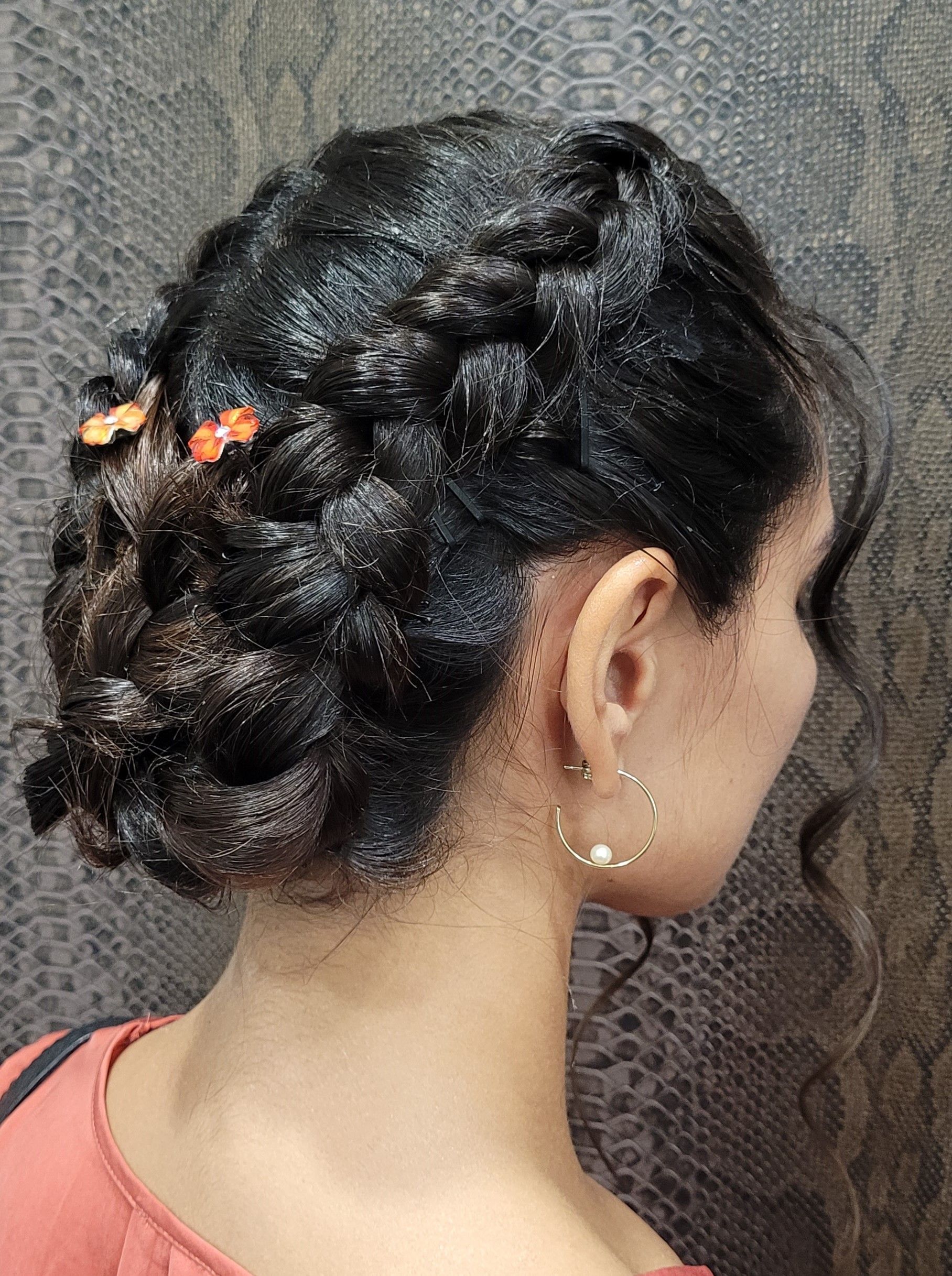 Una mujer lleva un moño trenzado y pendientes.