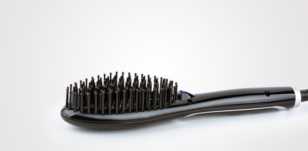 Un cepillo alisador de cabello negro está sobre una superficie blanca.