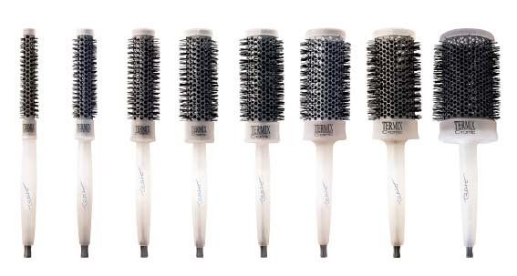 Una fila de diferentes tipos de cepillos para el cabello sobre un fondo blanco.