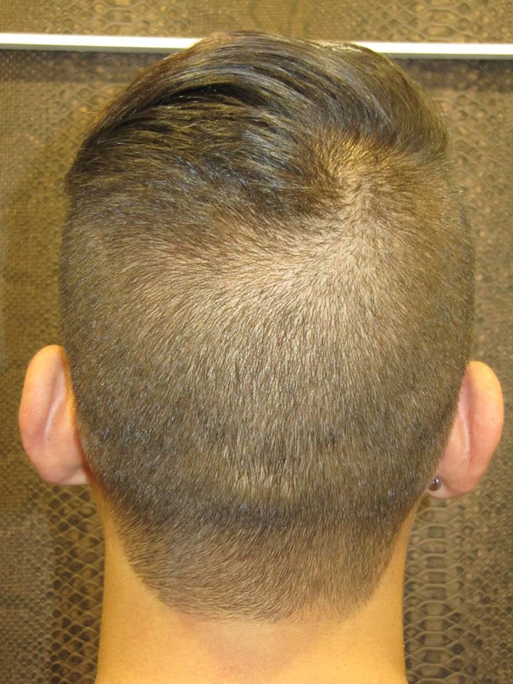 La parte posterior de la cabeza de una persona con la cabeza rapada y perforaciones en las orejas.