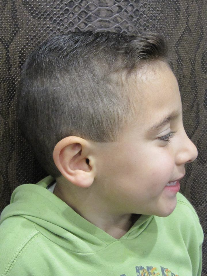 Un niño pequeño lleva una sudadera con capucha verde y sonríe.