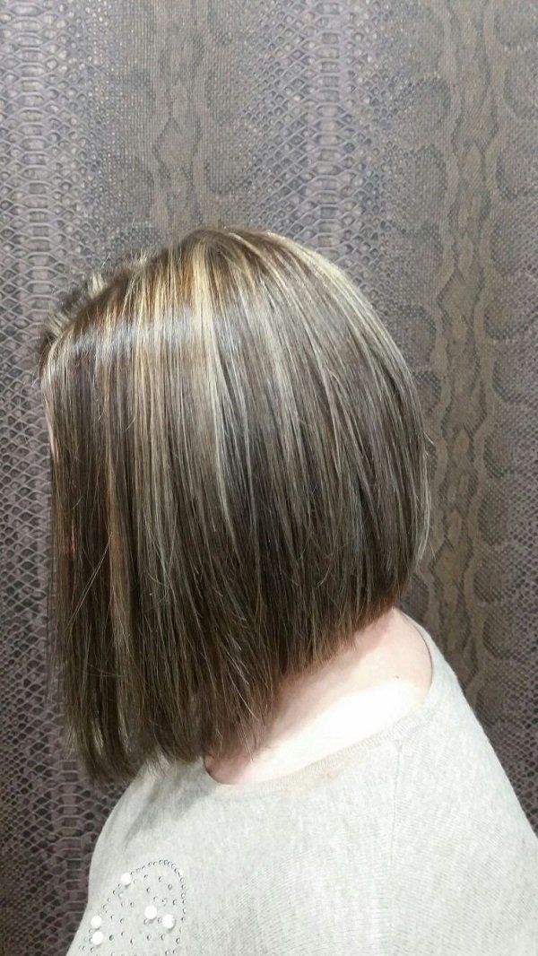 Una mujer con pelo corto lleva un suéter blanco.