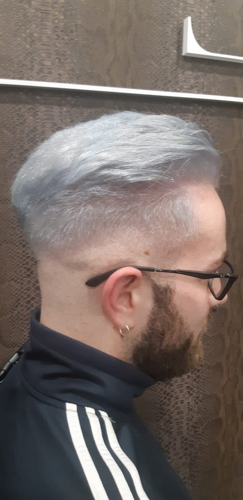 Un hombre con barba y gafas tiene el pelo gris.
