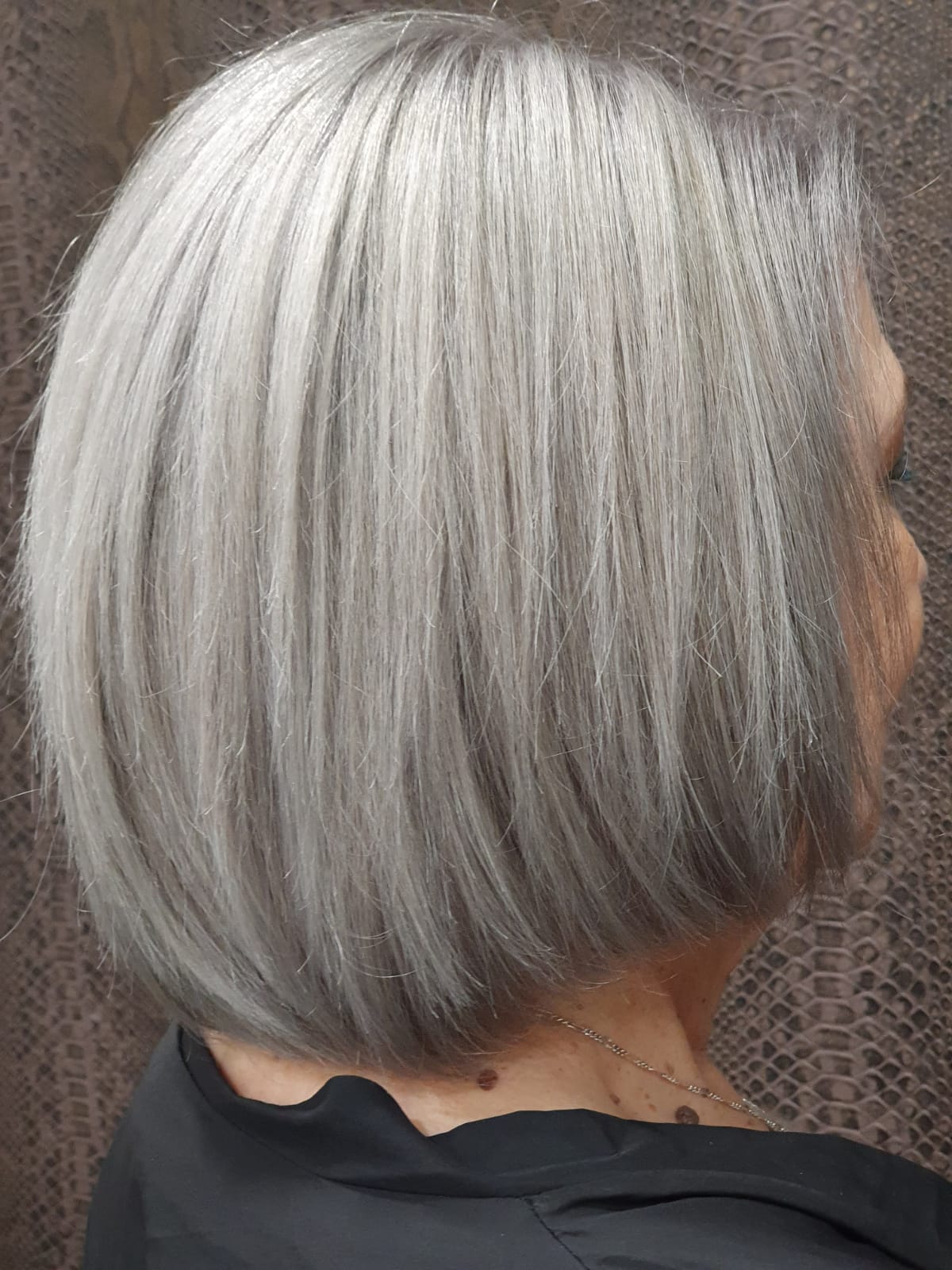Una mujer con cabello gris lleva una camisa negra y un peinado bob.