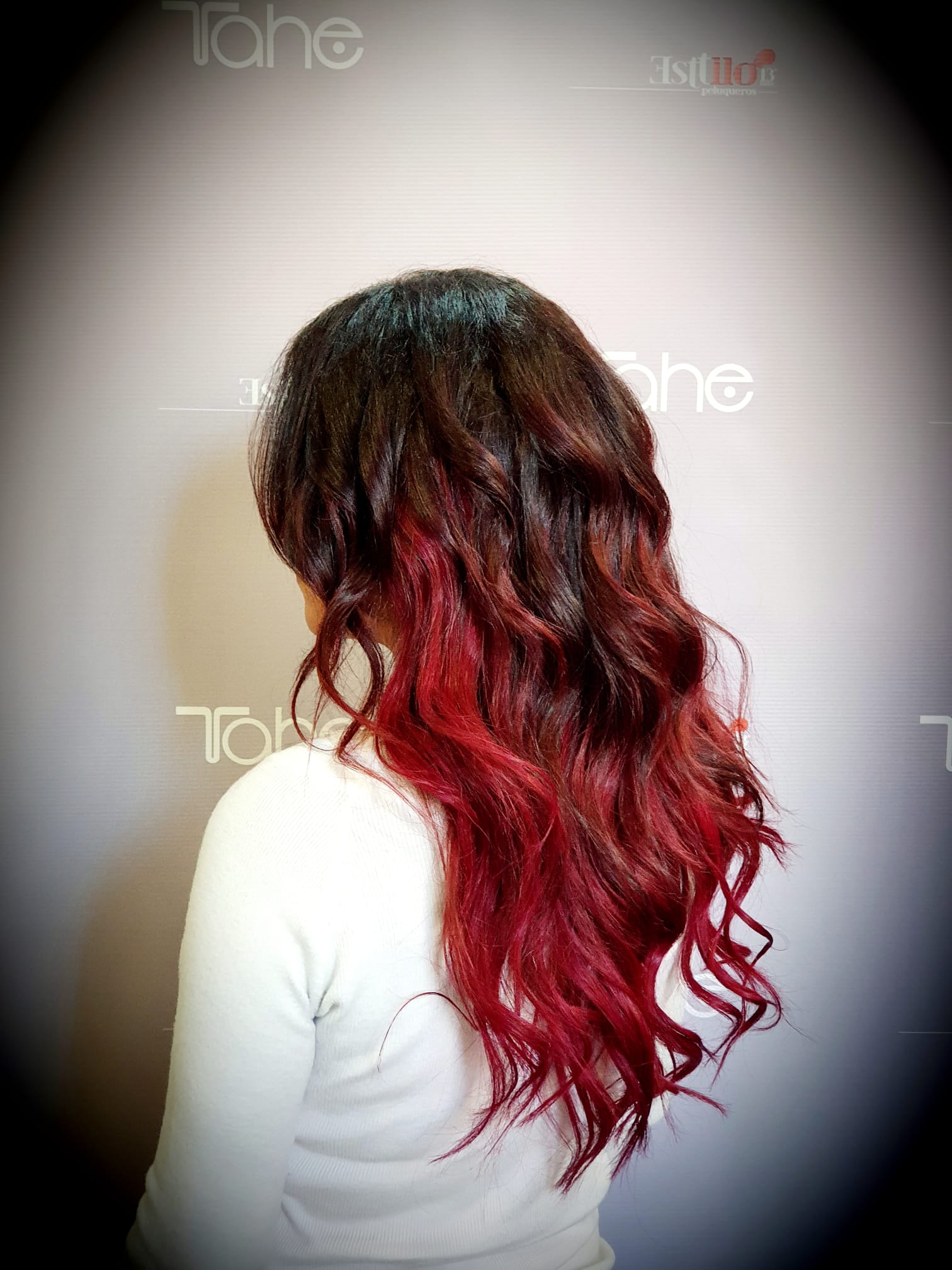 Una mujer con cabello largo y rojo lleva una camisa blanca.