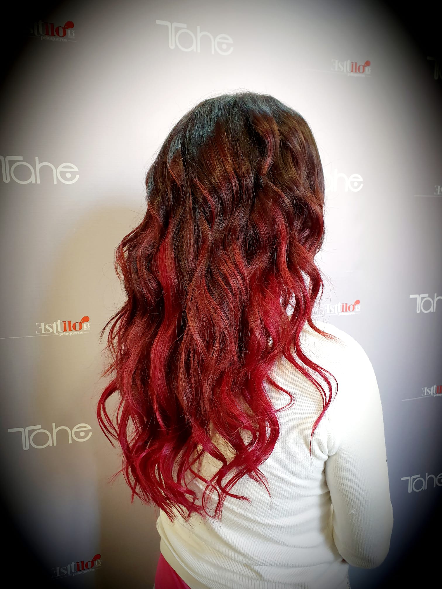 Una mujer con cabello largo y rojo lleva una camisa blanca.