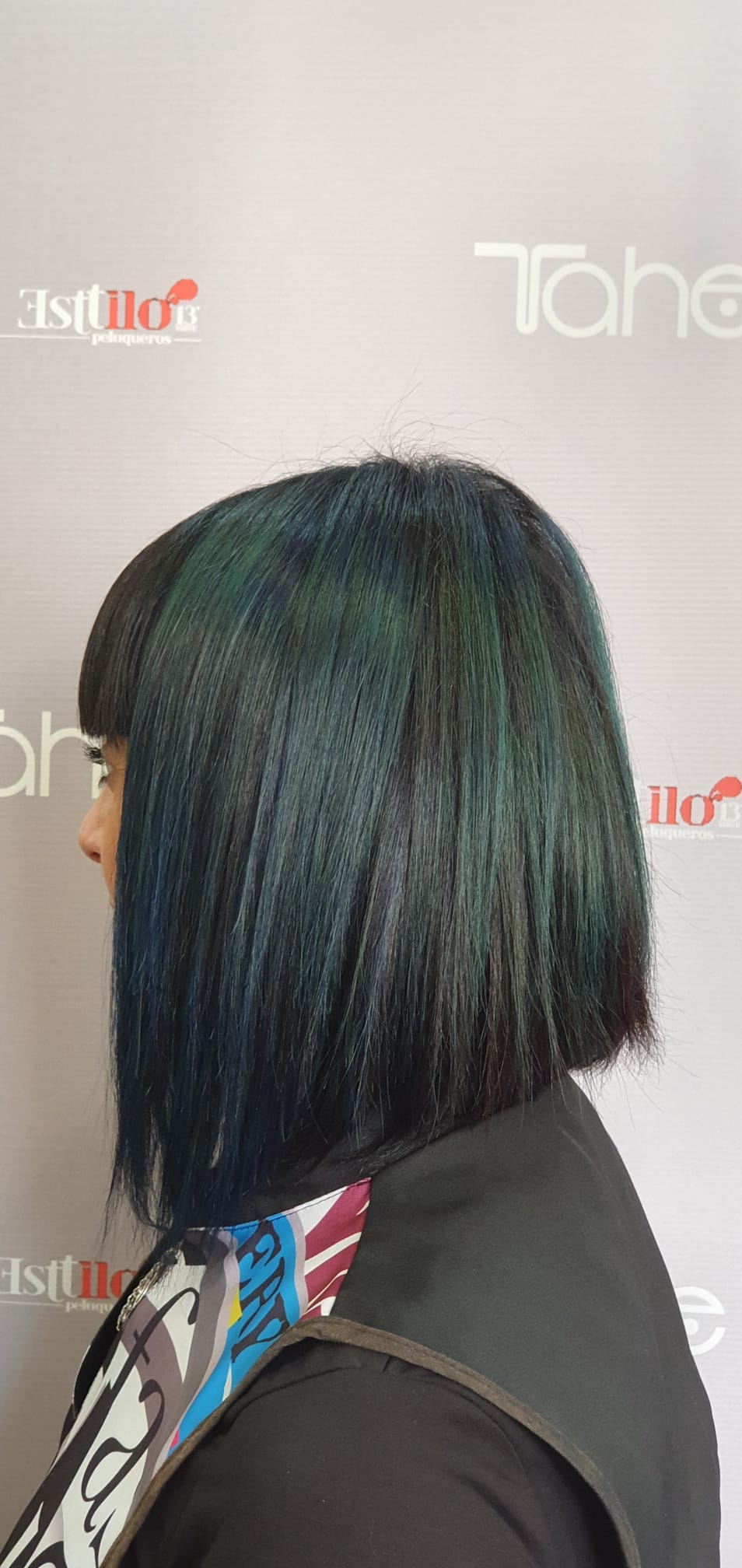 Una mujer con cabello azul lleva un delantal negro.