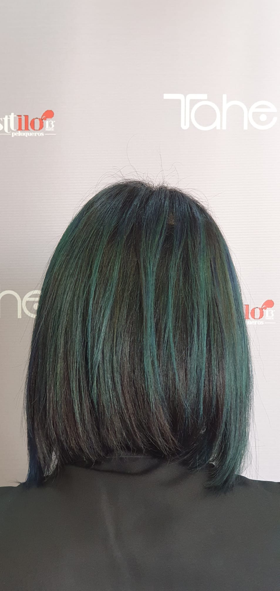 La parte posterior de la cabeza de una mujer con cabello verde.