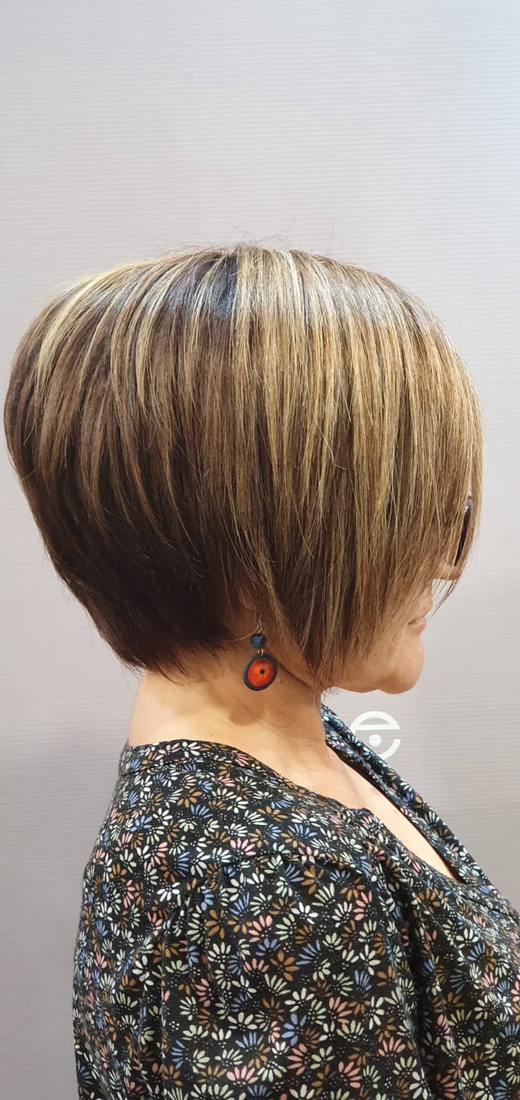 Una mujer con pelo corto y pendientes lleva una camisa floral.