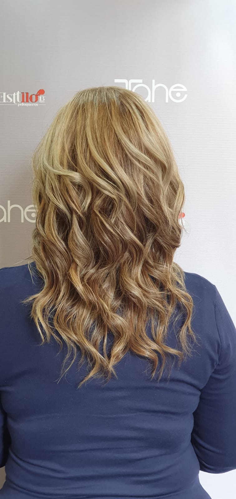 Una mujer con cabello largo y rubio lleva una camisa azul.