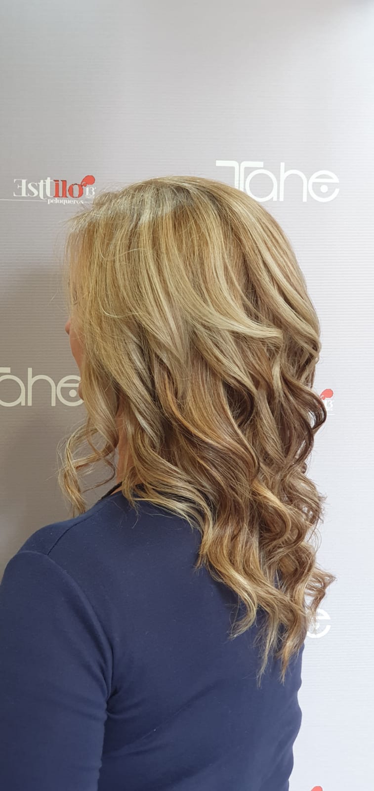 Una mujer con cabello largo y rubio lleva una camisa azul.