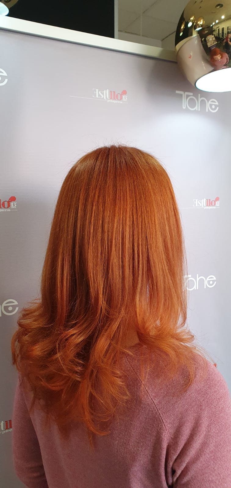 Una mujer con cabello rojo está parada frente a una pared.