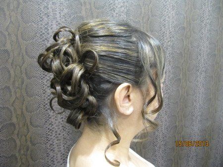 Una mujer con el pelo recogido en un moño está parada frente a una pared.