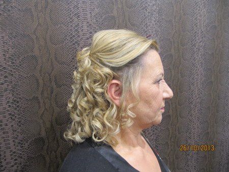 Una mujer con cabello rubio y rizado lleva una camisa negra.