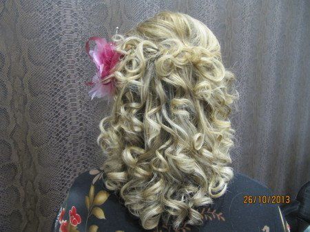 Una mujer con cabello rubio y rizado tiene una flor en el cabello.