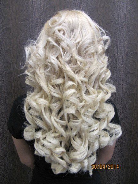 Una mujer con cabello largo rubio y rizado lleva una camisa negra.