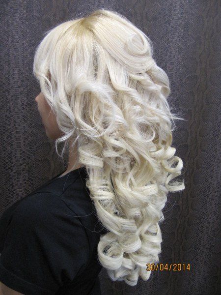 Una mujer con cabello largo rubio y rizado lleva una camisa negra.