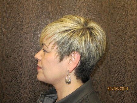 Una mujer con cabello rubio corto lleva aretes.