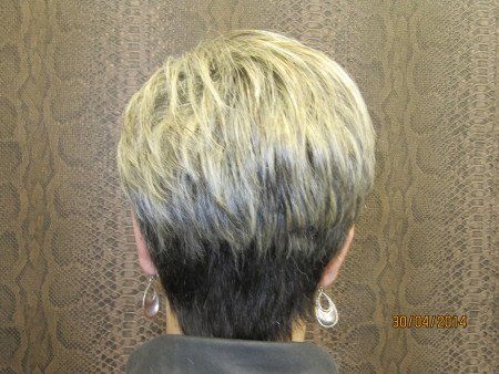 La parte posterior de la cabeza de una mujer con cabello rubio corto y aretes.