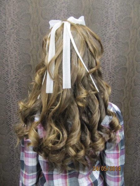 Una niña con un lazo blanco en el pelo lleva una camisa a cuadros.