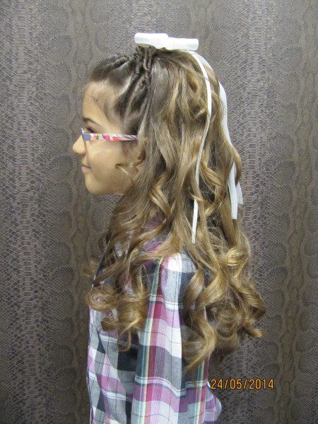 Una niña con cabello largo y rizado lleva gafas y una camisa a cuadros.