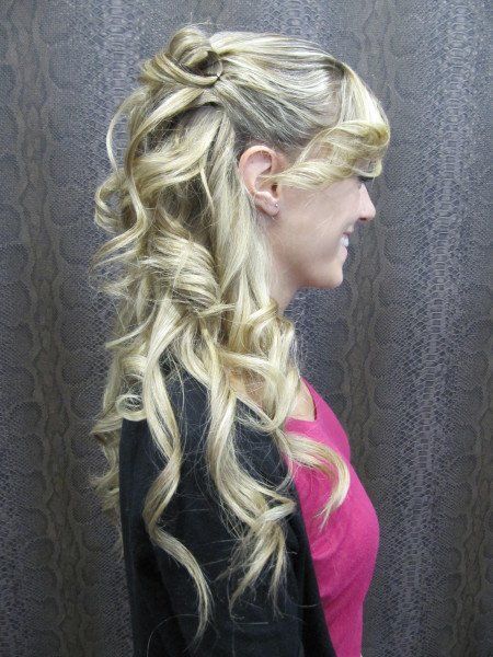 Una mujer con cabello largo y rubio lleva una camisa rosa y una chaqueta negra.