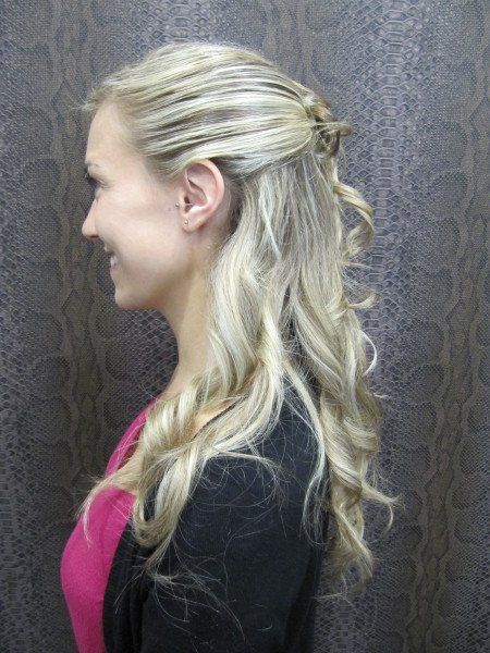 Una mujer con cabello largo y rubio lleva una camisa rosa y una chaqueta negra.