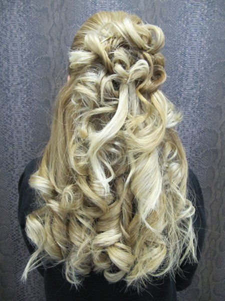 Una mujer con cabello largo rubio y rizado lleva una camisa negra.