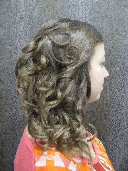 Una mujer con cabello largo y rizado lleva una camisa rosa y una bufanda.