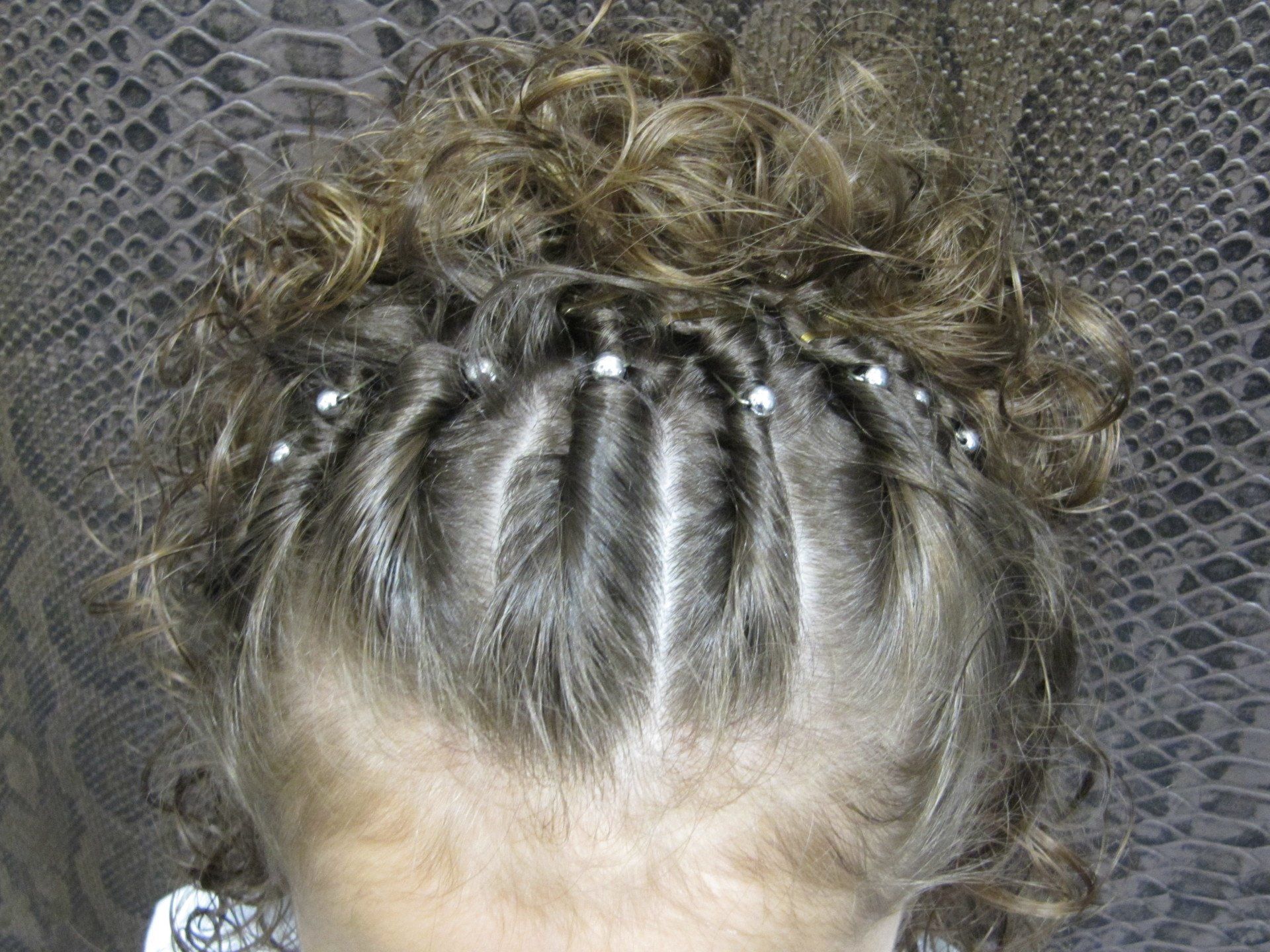 Una niña lleva el pelo recogido en un moño con cuentas.