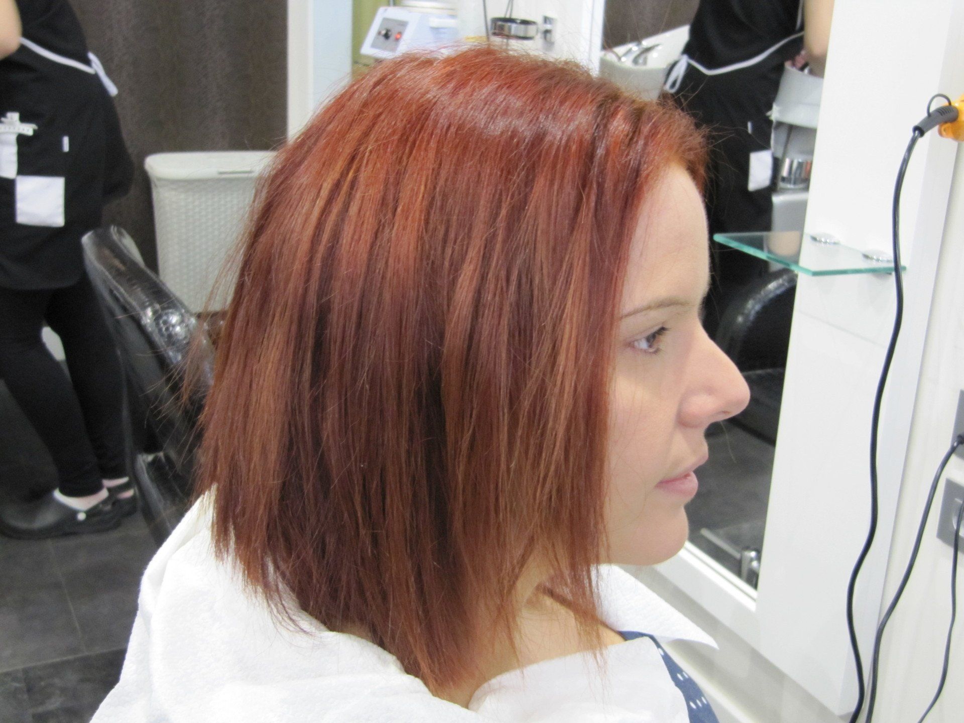 Una mujer pelirroja se está secando el pelo en un salón.