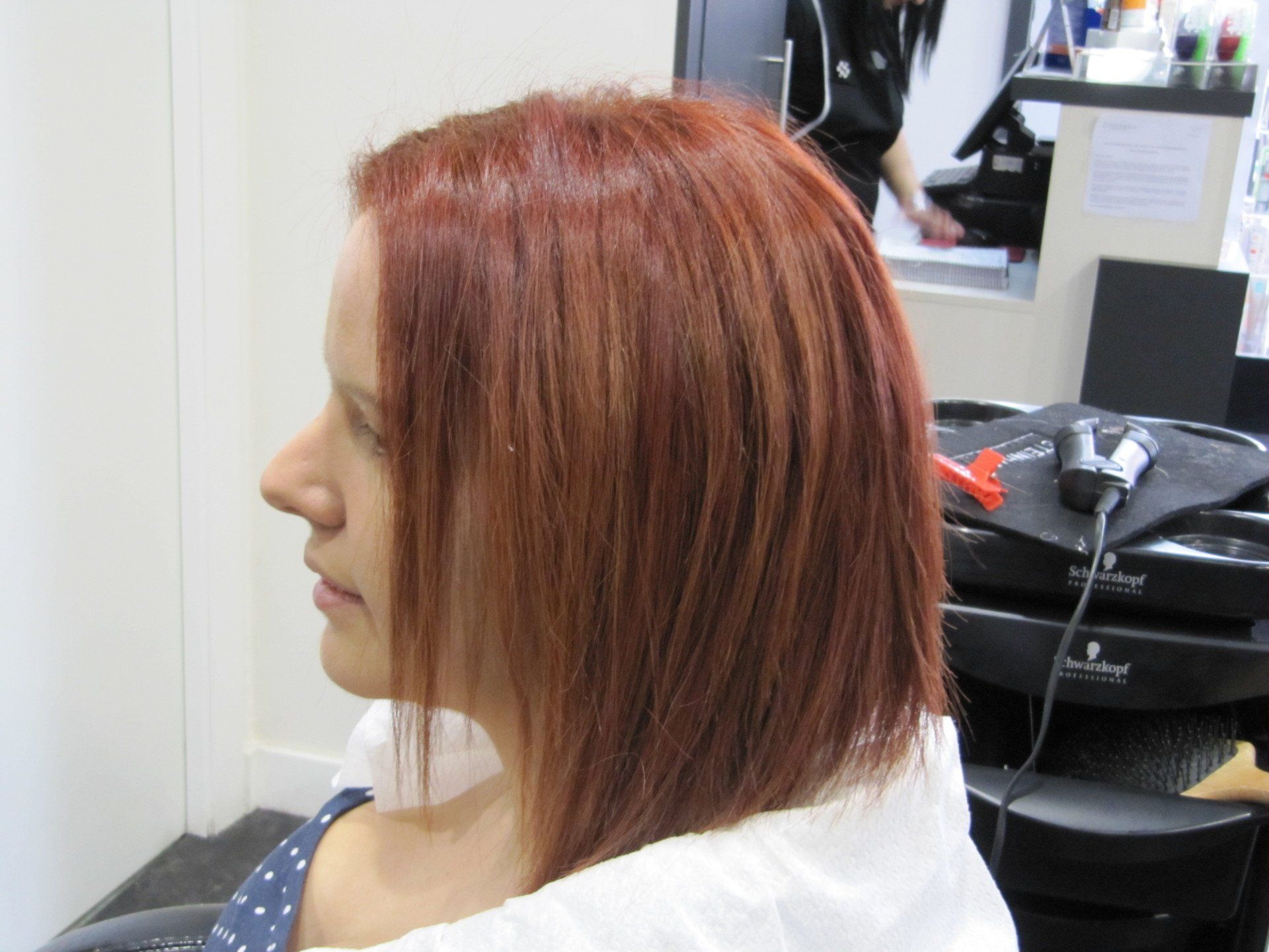 Una mujer pelirroja se está peinando en un salón.